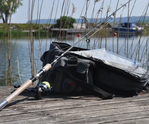 väska med redskap och fiskespö på brygga