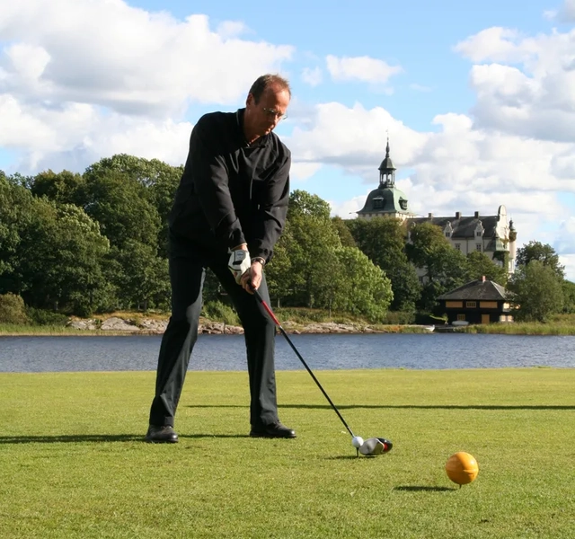 En man som slår en boll med en golfklubba.