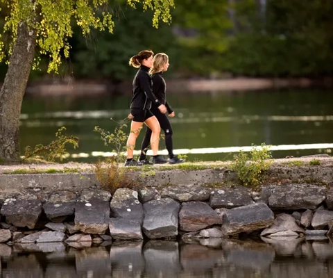Två personer som promenerar längs vattnet