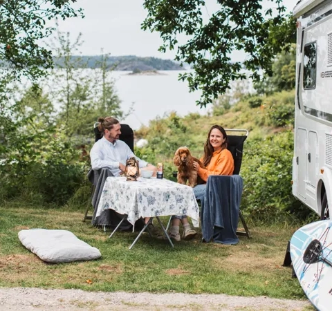 Människor sitter utanför en husbil.