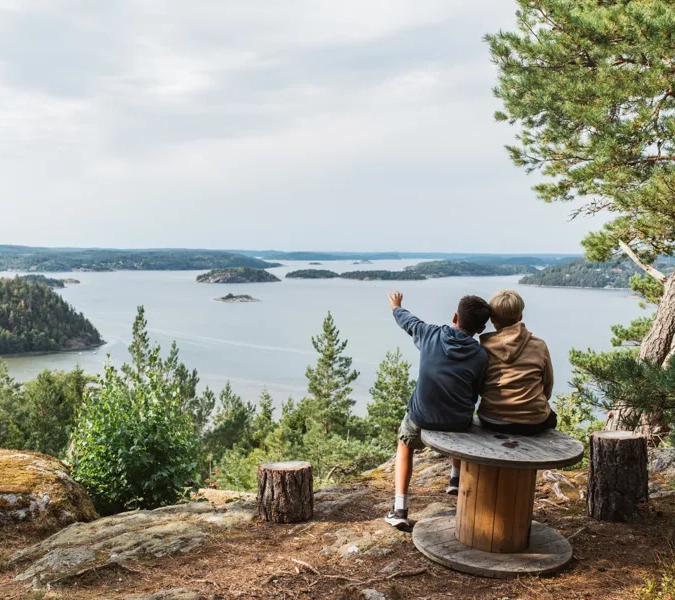 Two people sitting on a bench overlooking a lake.