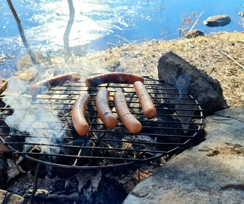 grillar korv utomhus i vårsolen