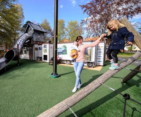 En kvinna och en ung flicka leker på en lekplats.