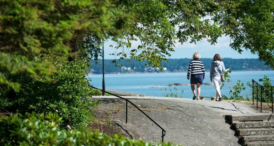 Två personer promenerar vid Vänerns vatten
