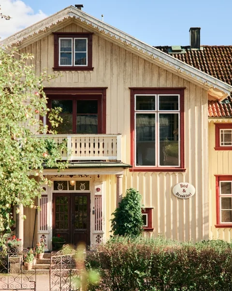 Ett gult hus med brunt tak och röda lister.