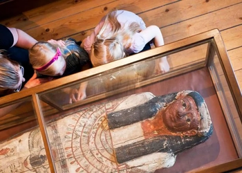 Barn som tittar på den egyptiska sarkofagerna i Vänersborgs museum,