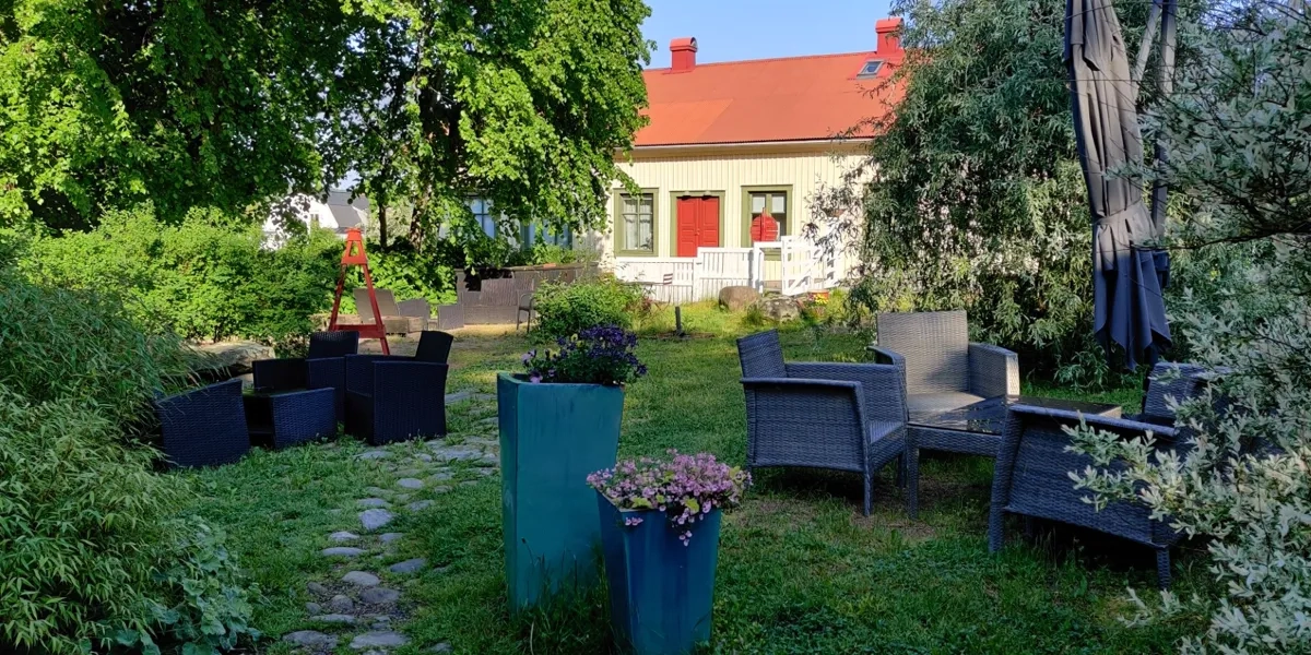 En trädgård med stolar och ett hus i bakgrunden.