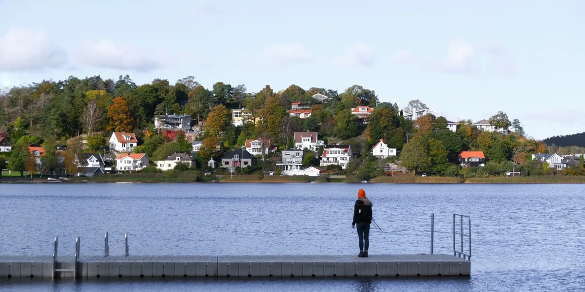 A person standing on a dock in the middle of a lake.