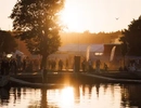 Solnedgång vid ett festivalområde med människor och tält