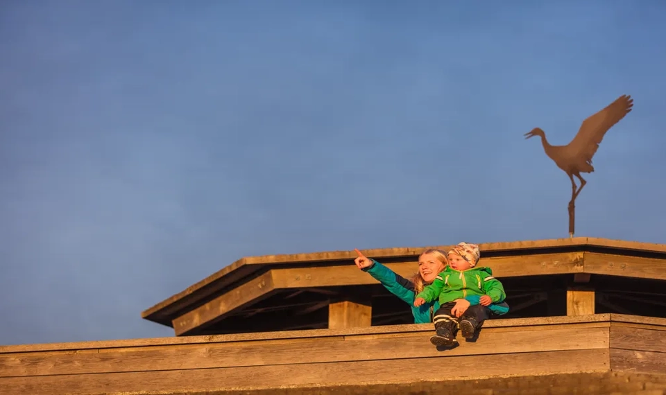 En mamma och ett barn sitter på toppen av ett fågeltorn.