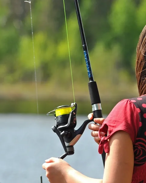 En liten flicka håller ett fiskespö och en fiskespö.