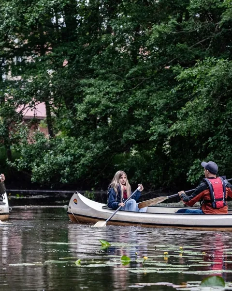 Två kanoter med en kvinna och barn i den ena och en man och barn i den andra.