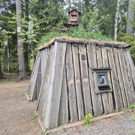 En liten träbyggnad med ett grönt tak.