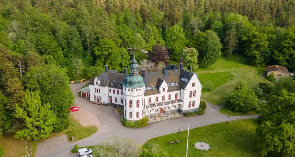 En flygbild av ett stort vitt hus omgivet av träd.