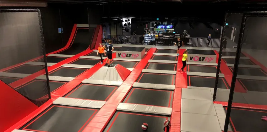 En stor trampolinpark inomhus med människor på den.