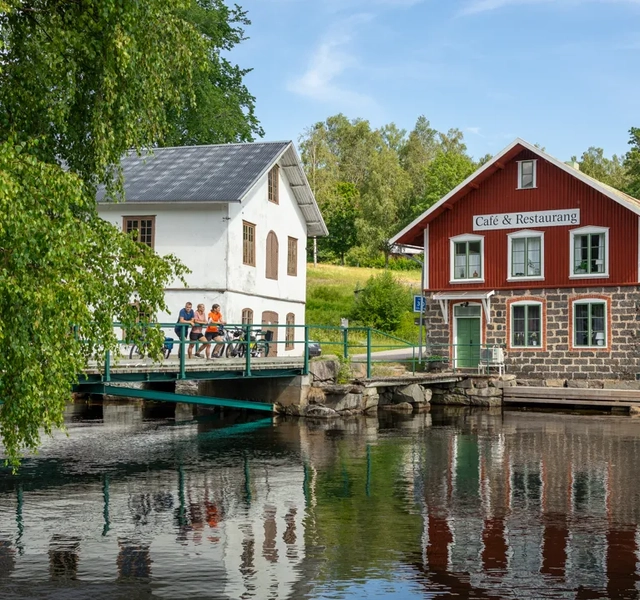 A red house sitting on top of a river next to a bridge.