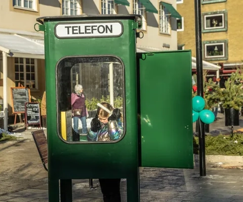 En flicka som står i en grön telefonkiosk.
