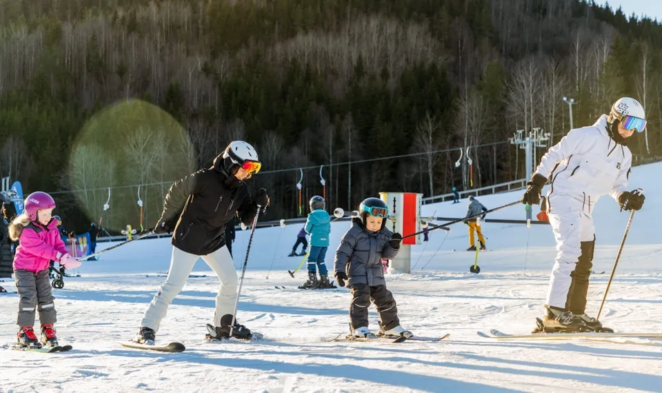 En grupp människor som åker skidor på toppen av en snötäckt sluttning.