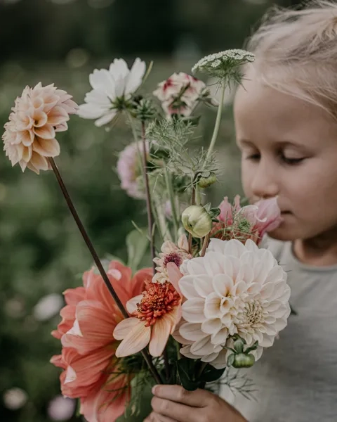 A little girl smelling a bunch of flowers.