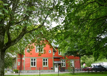 Gömd röd villa bakom träd.