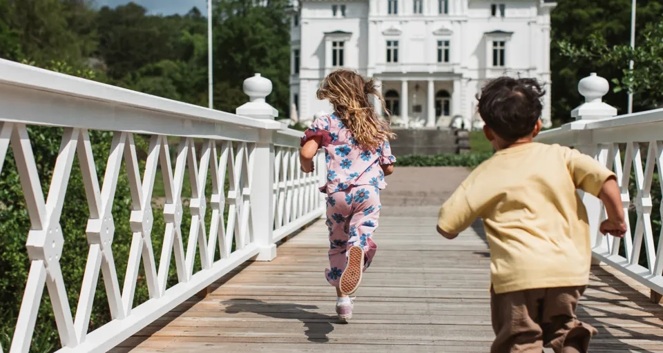 En pojke och en flicka springer över en bro.