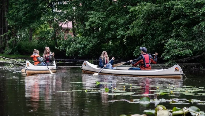 Två kanoter med en kvinna och barn i den ena och en man och barn i den andra.