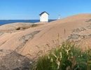 Ett litet hus på toppen av en stor klippa vid havet.