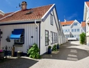 Ett litet vitt hus med en blå markis.