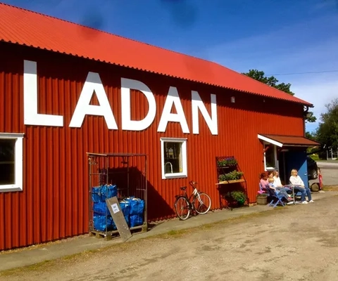 En röd byggnad med människor som sitter utanför den.