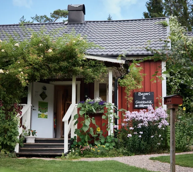 Ett litet rött hus med en vit veranda.