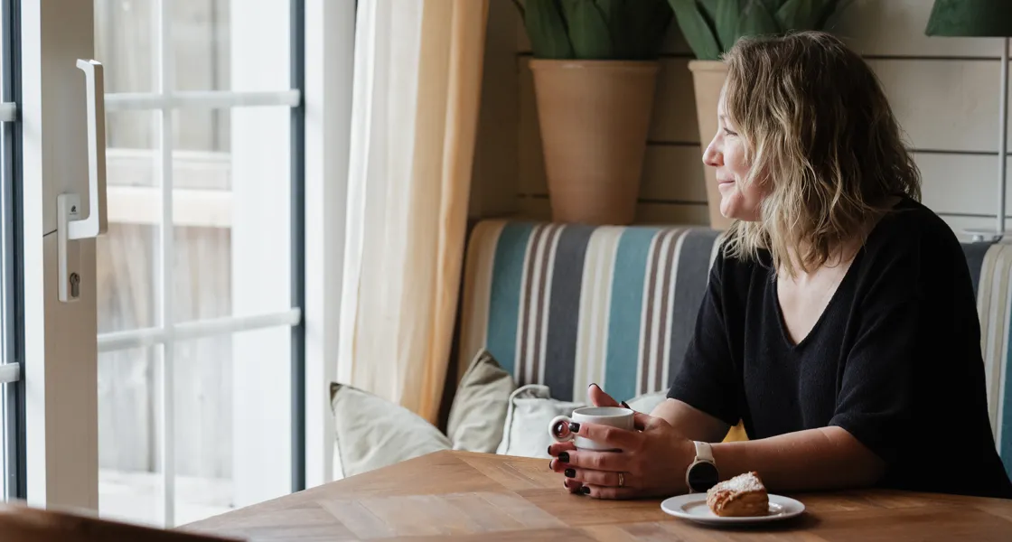 En kvinna sitter vid ett bord med en tallrik med mat.