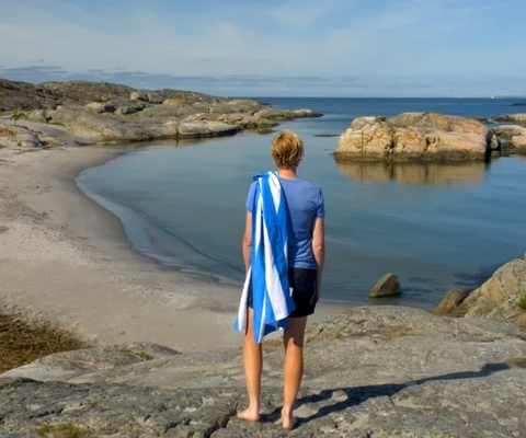 A person standing on a rock looking out at the ocean.