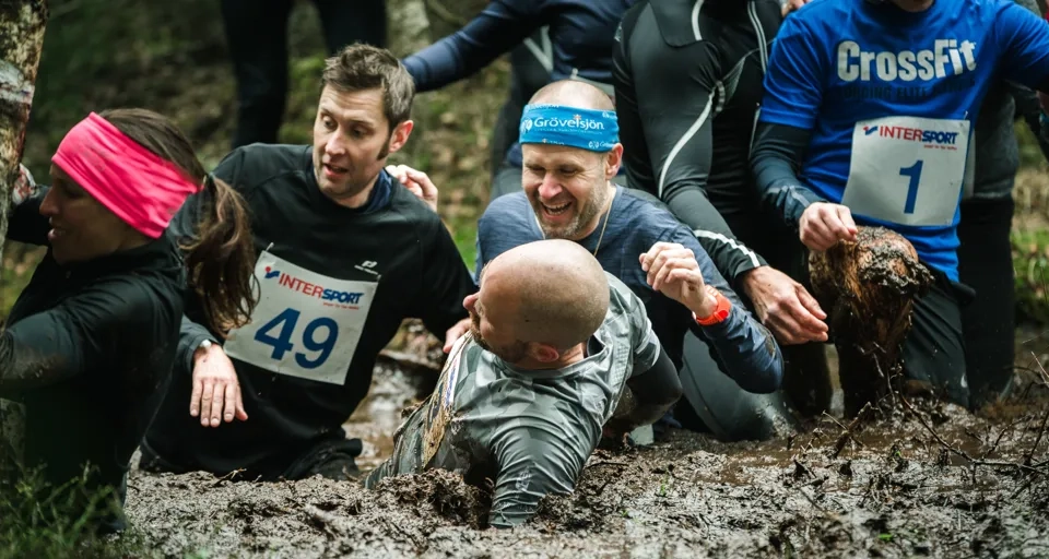 A group of people in the mud in a forest.