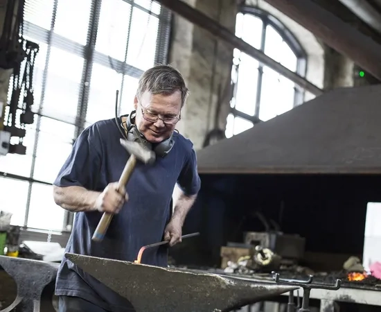 En man arbetar med ett metallstycke.