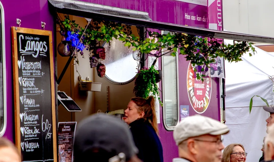 En grupp människor som står runt en food truck.