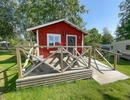 A small red cabin with a deck and a picnic table.