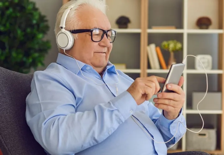 En man som sitter i en stol och lyssnar på musik med hörlurar på sig.