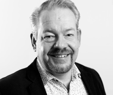 Ett svartvitt foto av en man som ler.