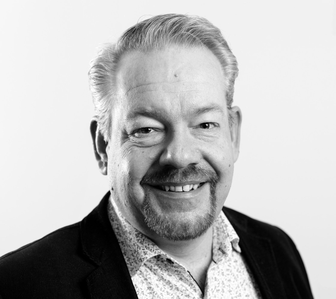 A black and white photo of a man smiling.