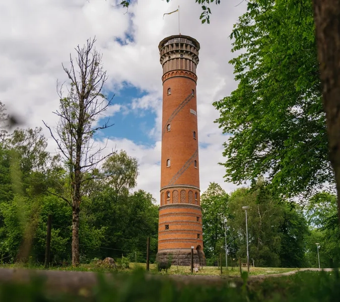 Utsiktstorn i rött tegel med träd och buskar runt omkring.