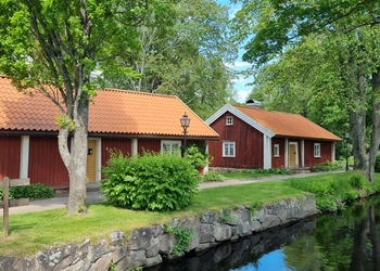 Vy över smedstugorna på Turbinhusön med ån Tidan framför.