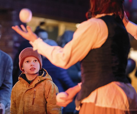 En ung pojke tittar när en kvinna jonglerar.
