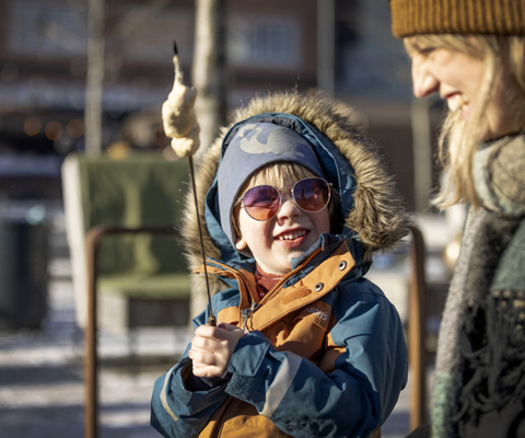 En kvinna och ett barn grillar pinnbröd utomhus.