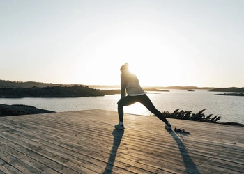 A person doing a yoga pose on a dock.