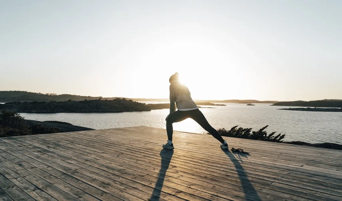 A person doing a yoga pose on a dock.