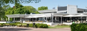 A building with a lot of tables and chairs in front of it.