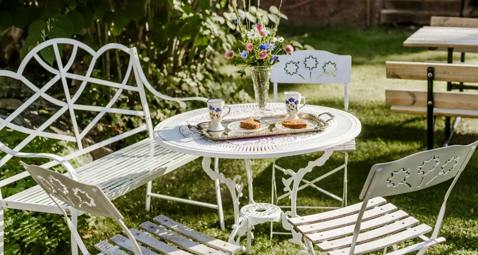 Ett vitt bord och stolar som sitter i gräset.