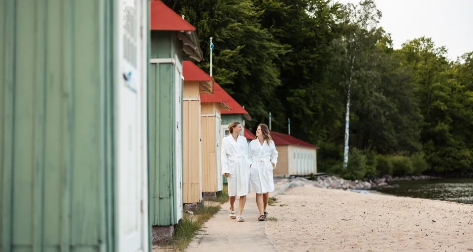 två kvinnor går längs badhytterna i hjo 