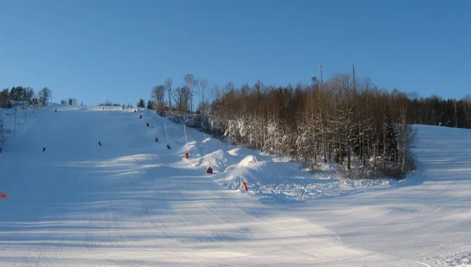 En snötäckt skidbacke med träd i bakgrunden.