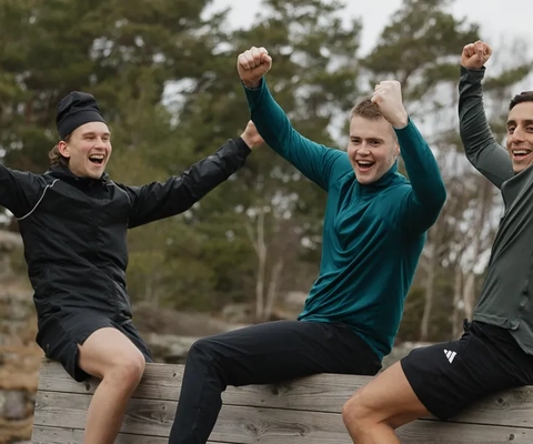 En grupp unga män som sitter på en träbänk.